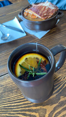 A cup of mulled wine with a slice of lemon and rosemary on a table