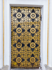 A black and gold door on a white wall