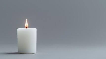 Lit white candle on grey background; serenity