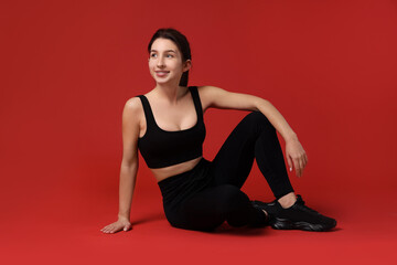 Fototapeta premium Portrait of woman in sportswear on red background