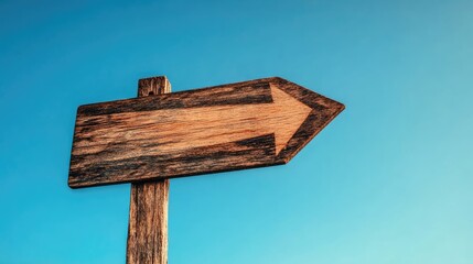 Fototapeta premium Wooden arrow sign against a clear blue sky