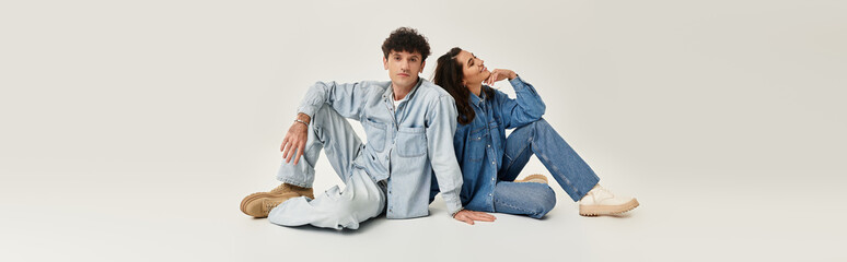 Young stylish couple showcasing trendy denim fashion against a minimalistic backdrop
