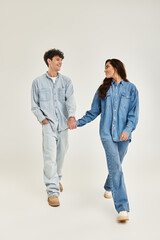 Young couple showcases trendy denim fashion in a minimalist studio setting
