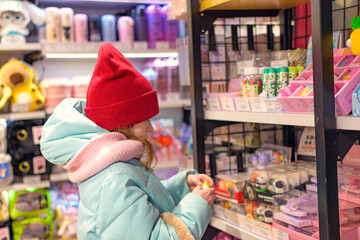 A girl chooses toys in a children's store. Shopping. 