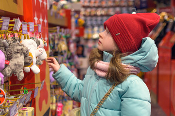 A girl chooses toys in a children's store. Shopping. 