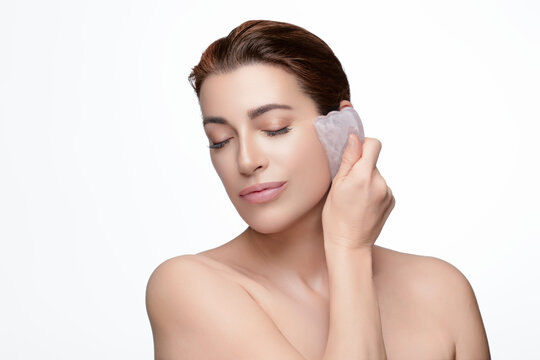 Woman performing facial massage with rose quartz gua sha tool