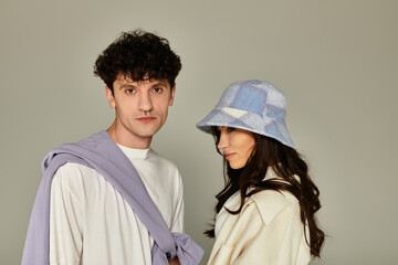 Stylish couple poses against a neutral background showcasing modern fashion trends