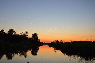 Obraz premium Beautiful view of sunset sky above reflected on calm river below