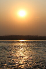 Naklejka premium Sunset over the ocean or river with a colourful sky and waves