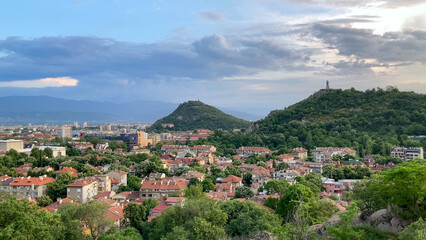 Scenic view of Plovdiv, Bulgaria, featuring the Alyosha monument, cityscape, lush hills, and cloudy sky. Take at Golden Hour.