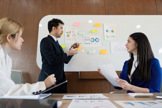 Diverse business team presenting financial analysis and strategies in a modern office environment. - Powered by Adobe