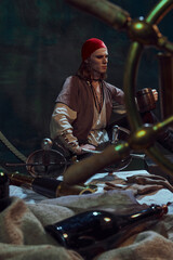 Young man in red bandana, pirate grips wooden mug, lost in thought. Nautical tools and maps surround him. Planning next adventure at sea. Concept of travel, history, exploration, adventure