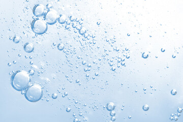 Transparent water bubbles rising in a blue liquid background for cosmetics advertisement. Refreshing, clean photo perfect for themes of purity, hydration, and freshness. Macro of hyaluronic acid
