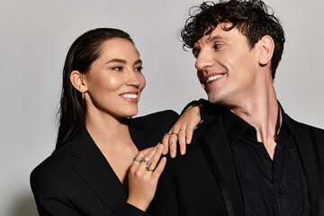 A stylish young couple shares a moment of joy, showcasing modern fashion in a sleek urban setting