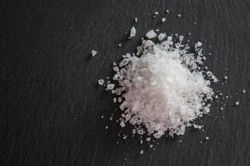 Food or drink. Pile of sea salt on a black natural background.