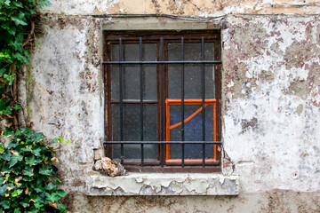 Close dirty rustic aged window in old house on the street.