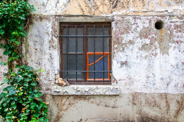 Close dirty rustic aged window in old house on the street.