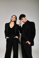 Young and stylish duo showcasing modern fashion trends in a minimalist studio setting