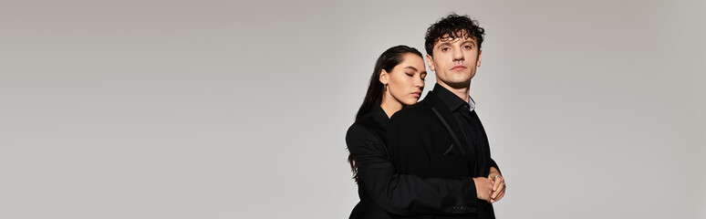 Stylish young couple showcases modern fashion against simple backdrop