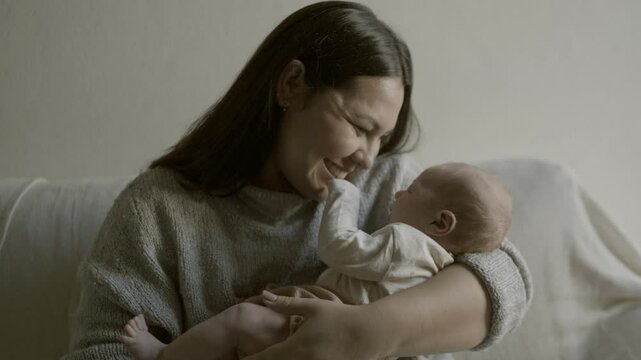 Love, care and mother on sofa with baby, bonding in home with happiness and playful new parent in living room. Relax, smile and happy young mom playing and holding calm newborn on couch in apartment.