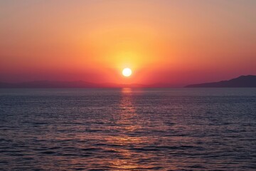 Obraz premium Sunset over the ocean creates vibrant sky colors and reflections on calm waters, highlighting serene beauty at the end of the day