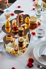 A three tier dessert tray with a variety of desserts including a pear tart