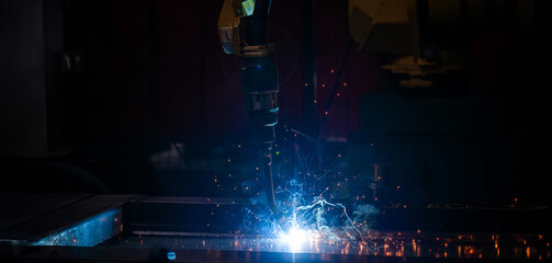 A machine is working on a piece of metal, creating sparks and heat