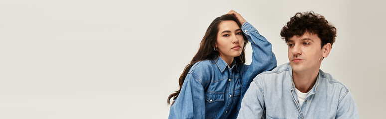 Stylish young couple showcasing contemporary denim fashion in a minimal setting
