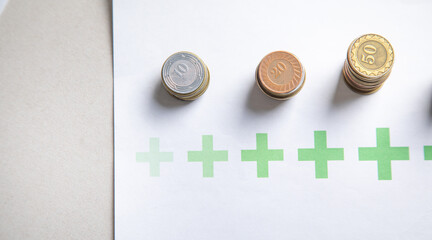Stack of coins with a growing plus signs.