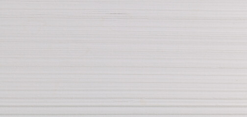 A stack of white paper is seen in close-up view. The horizontal lines created by the edges of each...