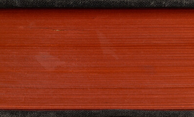A close-up of a thick, deep red book with tightly bound pages and a textured cover. The vibrant red...