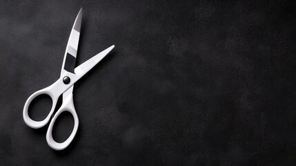 White scissors on dark surface, copy space