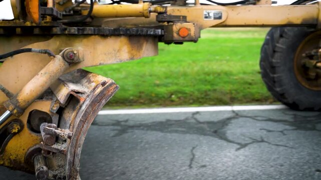 Close-up of Road Grader Clearing Grass from Road Edge at Construction Site for Asphalt Removal in Preparation of New Asphalt Layer