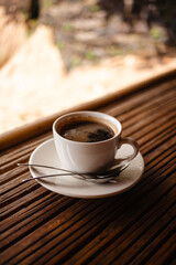 Hot Americano in a white mug on a table made of natural bamboo.