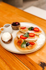 Pancakes with strawberries, fried bananas, ice cream and syrup on a wooden table. Delicious breakfast with fruits and berries