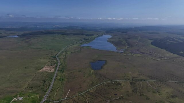 Barnesmore Gap, County Donegal, Ireland, June 2023. Drone pulls backwards at a high angle above Cashelnavean Bog with Lough Mourne visible in the distance on a bright sunny day.