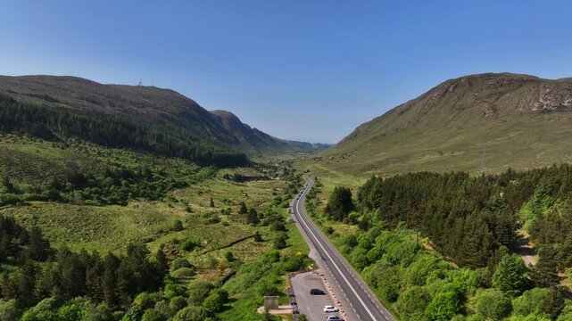 Barnesmore Gap, County Donegal, Ireland, June 2023. Drone pulls backwards and ascends above the winding N15 road as it provides a vital passage between rugged mountain peaks on a beautiful summer day.