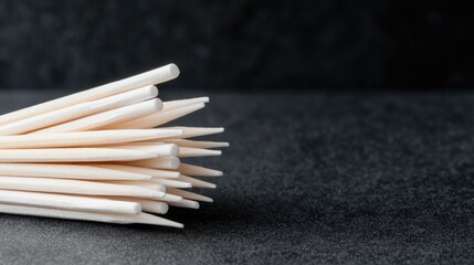 Obraz premium Wooden toothpicks on dark surface, close-up. Food hygiene, background blurred