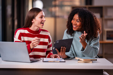 White businessman and African woman work as a team and use laptop tablet for night research. Data analysis results Comparing and planning with digital technology