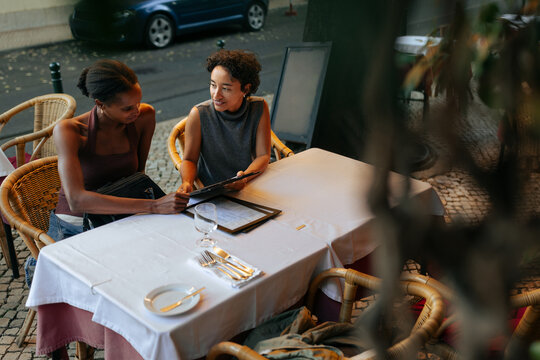 Two friends ordering food at a restaurant table, enjoying their vacation