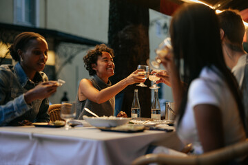 Friends toasting wine glasses during a dinner at a restaurant