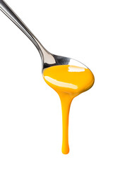 Yellow liquid, custard dripping from spoon with white background