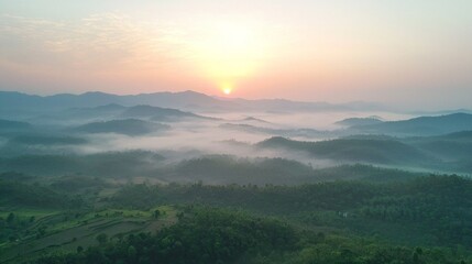 Obraz premium As the sun rises over the horizon, soft dawn light casts a warm glow on tranquil mountain valleys blanketed in mist. The serene landscape epitomizes peace and natural beauty