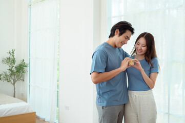 Fototapeta premium Couple Celebrating New Home Ownership With Miniature House Model in Cozy Living Room
