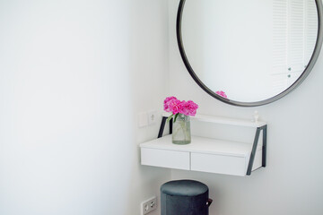 A vase with peonies on a white dressing table