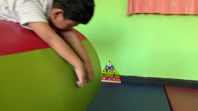 Child with cerebral palsy doing occupational therapy exercises on foam roller in clinic