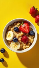 Warm oatmeal in a bowl with sliced banana and mixed berries on a sunny yellow background, honey, yellow background, banana