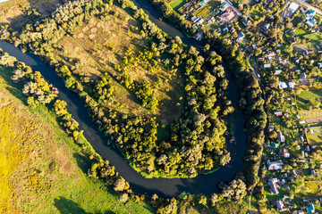 View from a great height of a riverbed with a sharp bend, a village on the bank of a small river