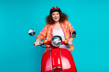 Young woman on a red scooter with a teal background exuding joy and trendy style