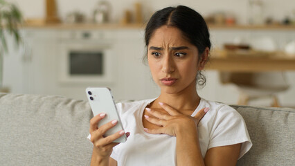 Gadget addict social media addicted Indian woman at home Arabian girl female using mobile phone male photo take picture selfie web camera posing vlogger influencer check result bad dissatisfied shock